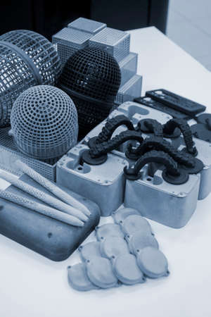 Many different models printed on 3D printer. Gray and black objects printedの写真素材