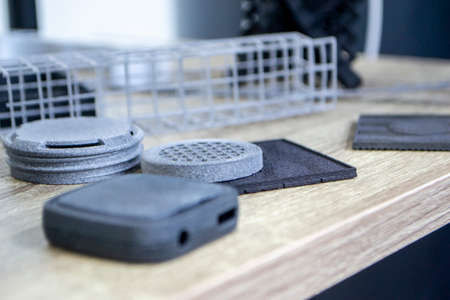 Many different models printed on 3D printer. Gray and black objects printedの写真素材
