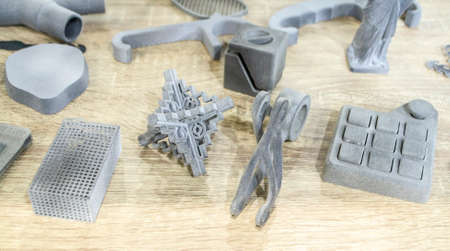 Many different models printed on 3D printer. Gray and black objects printed