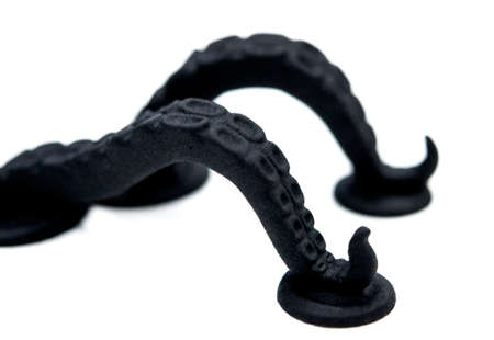 Models printed on 3D printer isolated on white background. Black objects octopus tentacles printed on 3D printer made of plastic close-up. Surface 3D printed models macro. Prototypes made by 3d printer.の写真素材