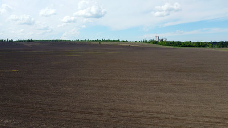 Aerial drone view flight over huge plowed field and blue sky. Skyline, horizon. Black earth. Agriculture, agricultural activities. Rural country landscape. Digging up the earth. Agronomy, farminの写真素材