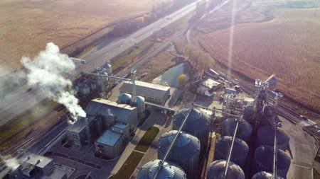 Aerial Drone View Flight Over complex of grain elevator buildings. Metal Round Silos and Metal Barrels for Grain Storage. Drying Storage Harvest. Elevator Tanks and Grain-drying complex. Large Granaryの写真素材
