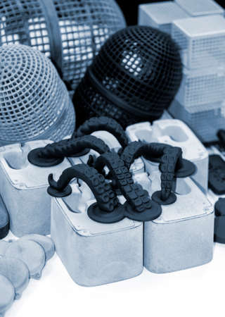 Many different models printed on 3D printer. Gray and black objects printed on 3D printer made of plastic close-up. Lots of 3D printed models. Prototypes of various shapes made by 3d printer on table.の写真素材