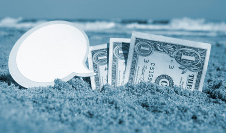 Paper bills one dollar, small stick clean empty paper speech bubble buried in sand beach background sea close-up in sunny summer day. Concept Money travel tourism vacation holiday. Blue white colorの写真素材