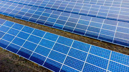 Aerial drone view flight over solar panels on sunny day close-up. Photovoltaic solar panel. Moving over solar panels with sun glare. Production of renewable alternative energy. Green ecological energyの写真素材