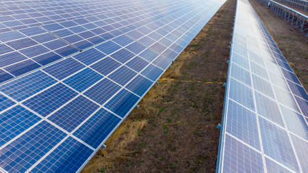 Aerial drone view flight over solar power station panels. Aerial top view of solar farm. Green energy, electrical innovation. Renewable Energy. Industrial Solar Energy Farm producing solar power.の写真素材