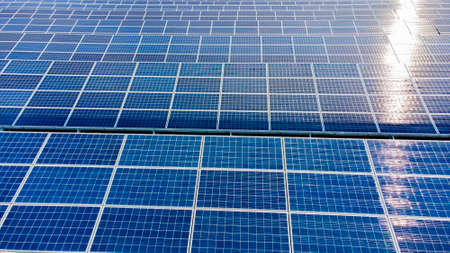 Aerial drone view flight over solar panels on sunny day close-up. Photovoltaic solar panel. Moving over solar panels with sun glare. Production of renewable alternative energy. Green ecological energyの写真素材