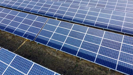 Aerial drone view flight over solar panels on sunny day close-up. Photovoltaic solar panel. Moving over solar panels with sun glare. Production of renewable alternative energy. Green ecological energyの写真素材