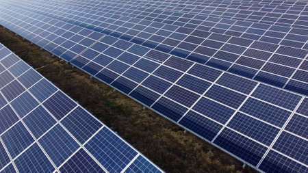 Aerial drone view flight over solar panels on sunny day close-up. Photovoltaic solar panel. Moving over solar panels with sun glare. Production of renewable alternative energy. Green ecological energyの写真素材