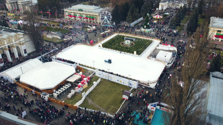 Kiev, Ukraine, January 2, 2022:-Aerial panoramic view cityscape urban park, outdoor ice skating rink and many people. Cleaning machine cleans ice rink. Public park. Lot of people. New Year Christmasのeditorial素材