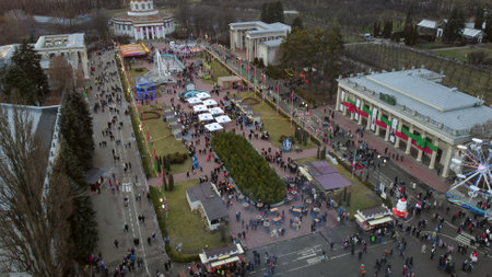 Kiev, Ukraine, January 2 2022:-Aerial panoramic view cityscape urban park outdoor, many people and old vintage buildings with columns. Cleaning machine cleans ice rink. Public park. New Year Christmasのeditorial素材