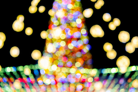 Large New Years Christmas tree decorated with luminous multi-colored garlands and illumination at night. Christmas tree with flashing lights. Blurred background. New Year and Christmas holidaysの写真素材