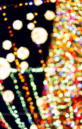 Large New Years Christmas tree decorated with luminous multi-colored garlands and illumination at night. Christmas tree with flashing lights. Blurred background. New Year and Christmas holidaysの写真素材