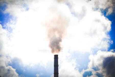 top tube factory with smoke from it against the sky with a bright sunlit white clouds, filterの写真素材