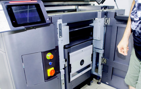 A man worker and a large industrial powder 3d printer in a laboratory in a factory. Multi Jet Fusion. Industrial equipment. New modern 3D printing , additive progressive technology. MJFの写真素材