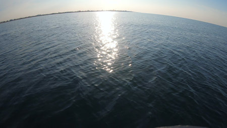 Seascape, view of sea waves with sun reflection from prow of motorboat. Boat jumping on waves on sunny summer day. Yacht motor boat sailing fast at sea horizon. Extreme sport entertainment backgroundの写真素材