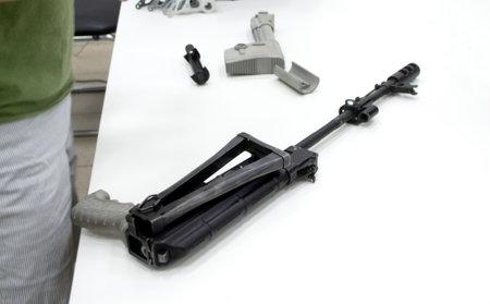 3D printed weapon parts. Man assembles weapon rifle, some parts printed on 3D printer. Details of gray color of weapon printed on 3D printer from polyamide powder. Progressive additive technologyの写真素材
