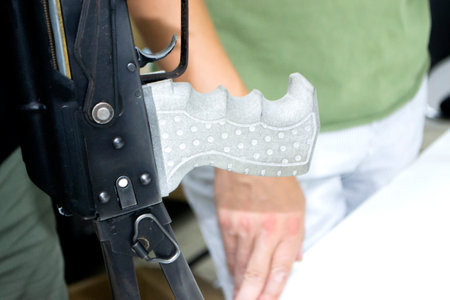 3D printed weapon parts. Man assembles weapon rifle, some parts printed on 3D printer. Details of gray color of weapon printed on 3D printer from polyamide powder. Progressive additive technologyの写真素材