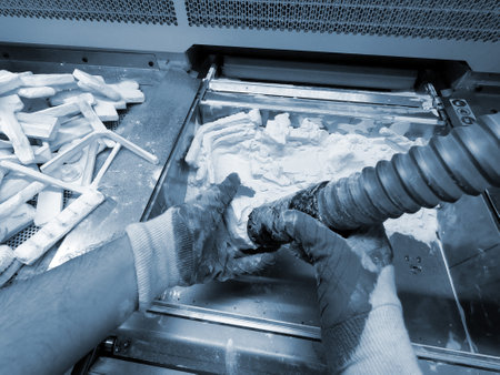 Male worker taking out models from white polyamide powder in working chamber of 3D printer, cleaning powder and putting on surface. Process of creating model on powder 3D printer. Multi Jet Fusion MJFの写真素材