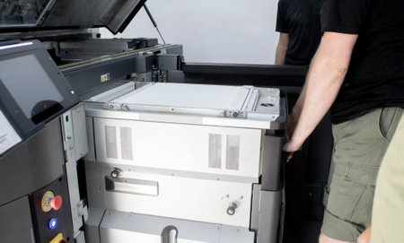 A male worker pushes a working chamber with white polyamide powder into a 3D printer. Large industrial 3D printer printing with polyamide powder in laboratory. Multi Jet Fusion. Industrial equipmentの写真素材