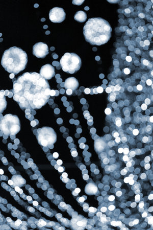 Blurred background. Beautiful luminous and flashing New Year Christmas decoration garlands and glowing balls for Christmas tree hanging outdoors night.Blurry blinking bokeh spots backdrop Blue colorの写真素材