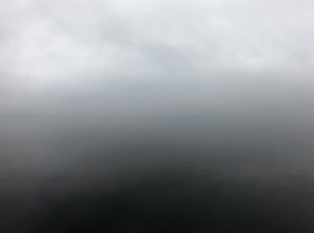 Calm sea cloudy weather. Smooth waveless sea surface in windless cloudy weather. Calmness. Gray rain...