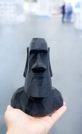 A person holding a model printed on a 3D printer from black plastic on his hand close-up.の写真素材