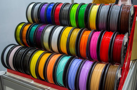 Many multi-colored spools of thread of filament for printing 3d printer. Material coils for printing 3D printer. Spools of 3D printing motley different colors filament. ABS wire plastic for 3d printerの写真素材