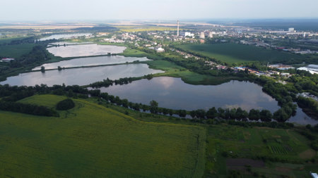 Beautiful panoramic urban landscape on summer day. Industrial lakes for fish farming, agricultural farm fields, city Industrial Zone building, thermal power plant. Aerial drone view. Top viewの写真素材