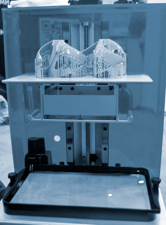 Printed models on 3D printer close-up. Objects printed on photopolymer sla 3D printer from liquid photopolymer resins on printing platform inside 3d printer. Modern progressive additive technology.の写真素材