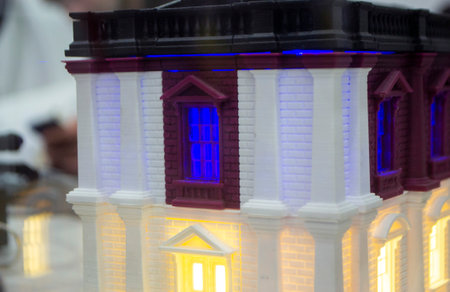 Prototype printed on 3D printer brick building with columns and glowing windows. Model of building...