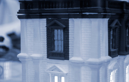 Model of building with white and black color, windows with light shining, created by 3D printer from molten plastic. Prototype printed on 3D printer brick building with columns and glowing windows.の写真素材