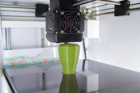 3D printer close up. A working 3D printer in process of printing object from molten plastic. 3D printer creating model by flowing liquid plastic from an extruder of printer. 3D printing technologyの写真素材
