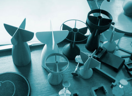 Prototype model of rocket tip printed on 3D printer. Small models of tail fins, tail cone printed on 3D printer from molten plastic on table. New modern innovation printing technologyの写真素材