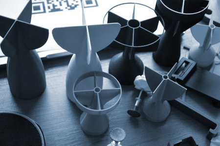 Prototype model of rocket tip printed on 3D printer. Small models of tail fins, tail cone printed on 3D printer from molten plastic on table. New modern innovation printing technologyの写真素材
