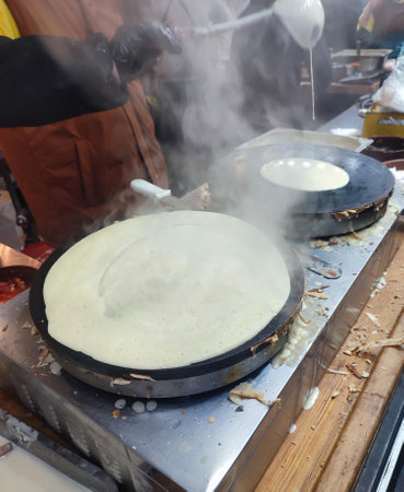 Person pouring ladle of batter into round pan for frying pancakes. Cook making pancakes from fried...