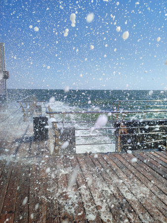 Wave hitting wooden pier jetty with a lot of splashes on a sunny day. Stormy sea. Weather. Travel,...