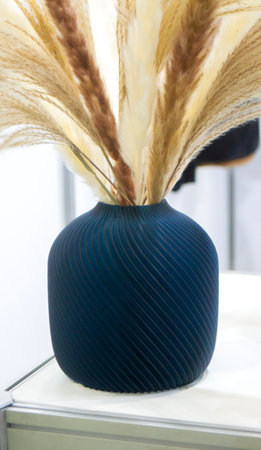 Beautiful dark vase with dried flowers printed on 3D printer on table. Model created by 3D printer...