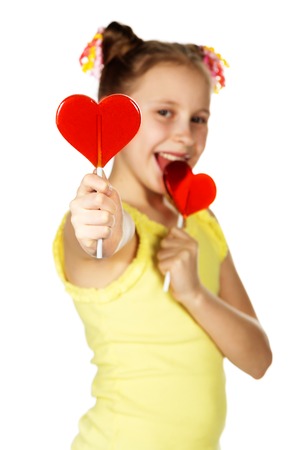 Lollipop in the shape of heart fashion smiling teen girl holds treating, the second holds a lollipop in his mouthの写真素材