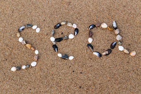 Word sea made of shells and pebbles on the sand drawn upの写真素材