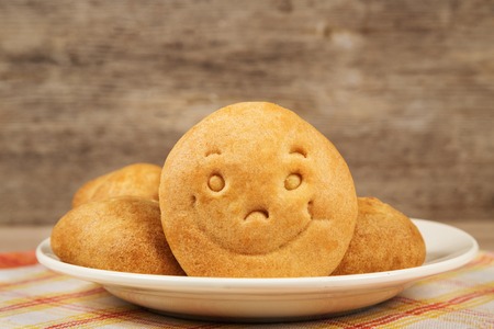 Cookie with a smile on a plate on wooden background textureの写真素材