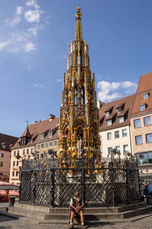 SchÃ¶ner Brunnen in Nuremberg's Hauptmarkt, a famous Gothic-style fountain inspired by a 14th-century spire, captured in bright daylight in the historic market square.の写真素材