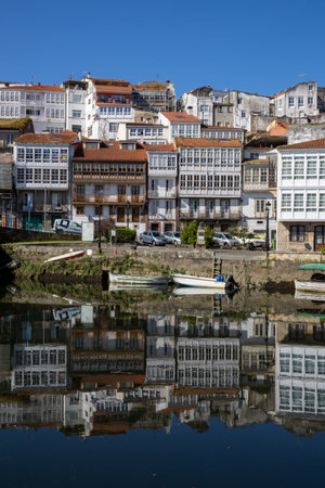 Scenic view from Praza a Enrique Ivntiga Eira Vella, Betanzos, Galicia, with riverside white homes and boats reflecting on the peaceful Mandeo River.の写真素材