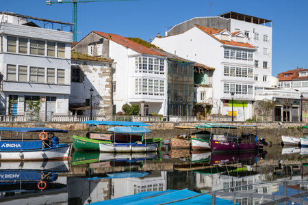 Traditional Galician white buildings seen from Ponte Vella bridge over Mandeo River in Betanzos, Spain, surrounded by lush greenery.の写真素材