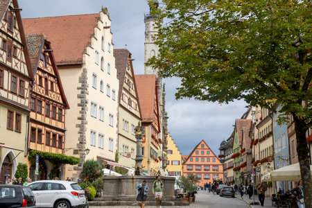 Colorful historic street Herrngasse with Herrnbrunnen fountain and traditional half-timbered buildings in Rothenburg ob der Tauber, Bavaria, Germany, medieval town travel scene.の写真素材