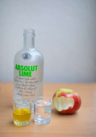 A bottle Absolut Vodka, one small glass Absolut Vodka and oil and apple on the wooden table. Warsaw,...