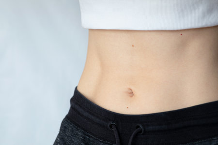Flat female belly. Woman showing her flat athletic belly. Visible moles on the abdomen