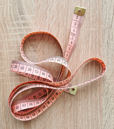Single pink tailor meter on a wooden table. A measuring instrument used in sewing clothes and taking...
