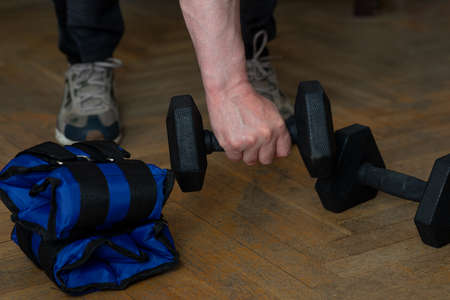 Equipment for exercising the muscles of the arms and legs. Weights and sandbags on the wooden floor....