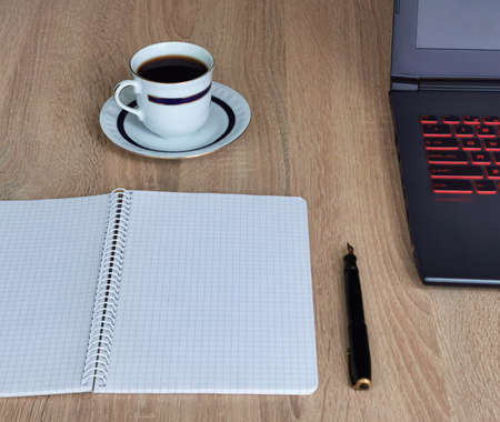 Close up cup of coffee, laptop computer, notebook and pen on wooden desk office. Workplace at homeの写真素材